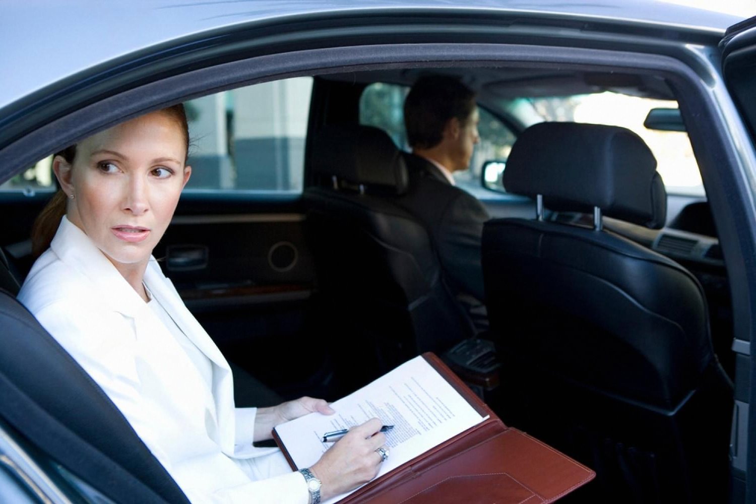 Businesswoman working in the back seat of a chauffeur-driven car in Dubai