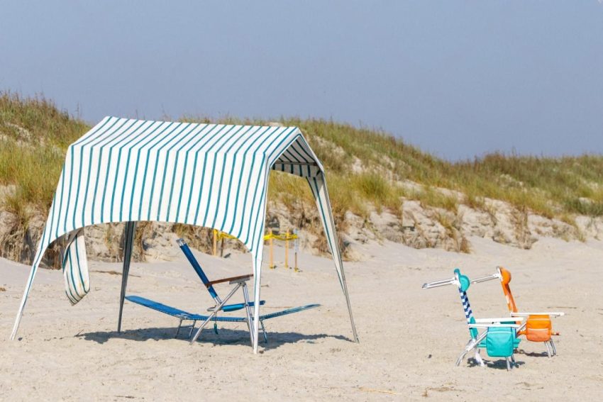 Striped canopy tent set up on a Dubai beach with lounge chairs underneath, illustrating outdoor event tent rental